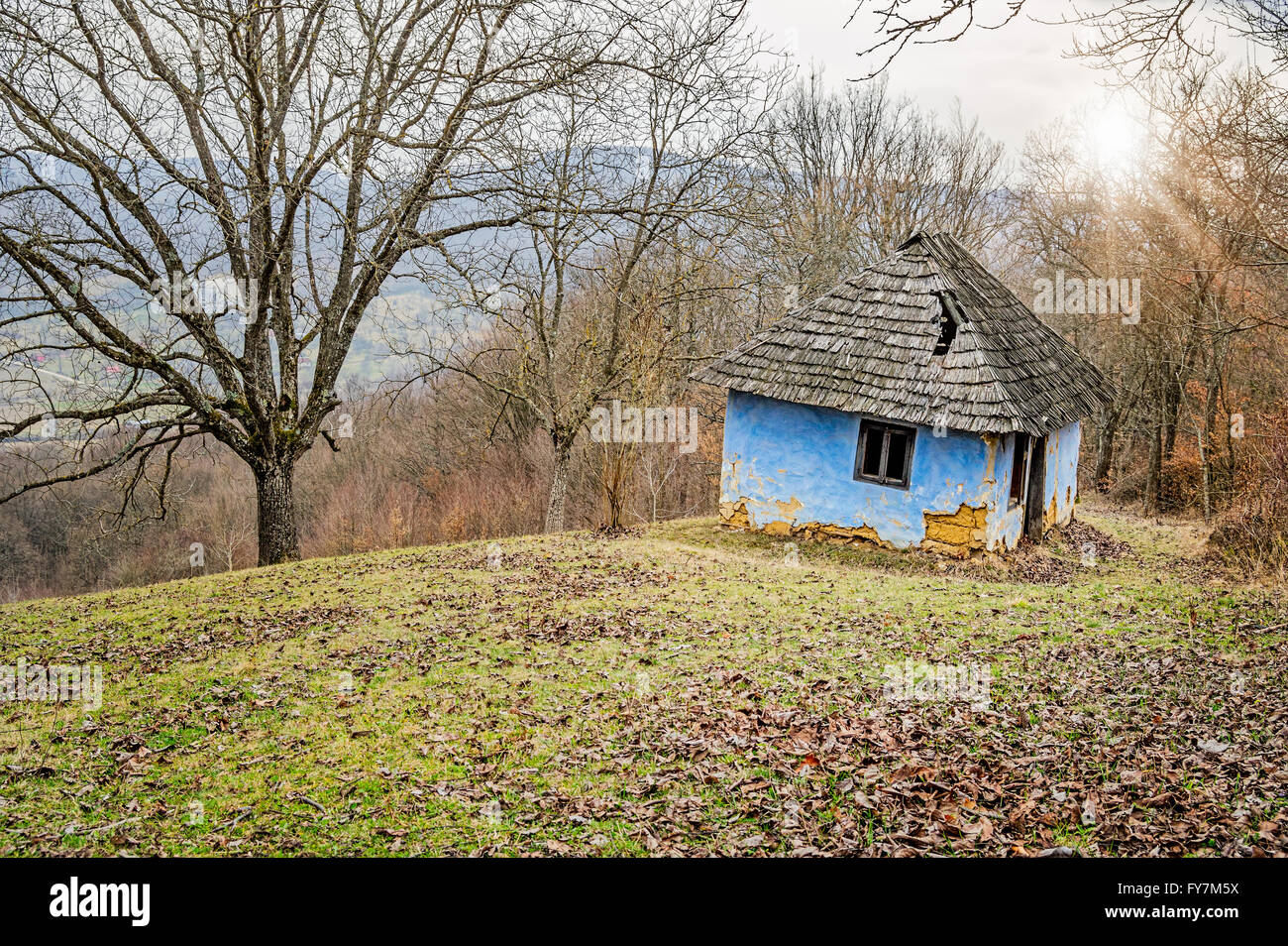 Ruined blue old house made of clay in the hills surrounded by trees ...