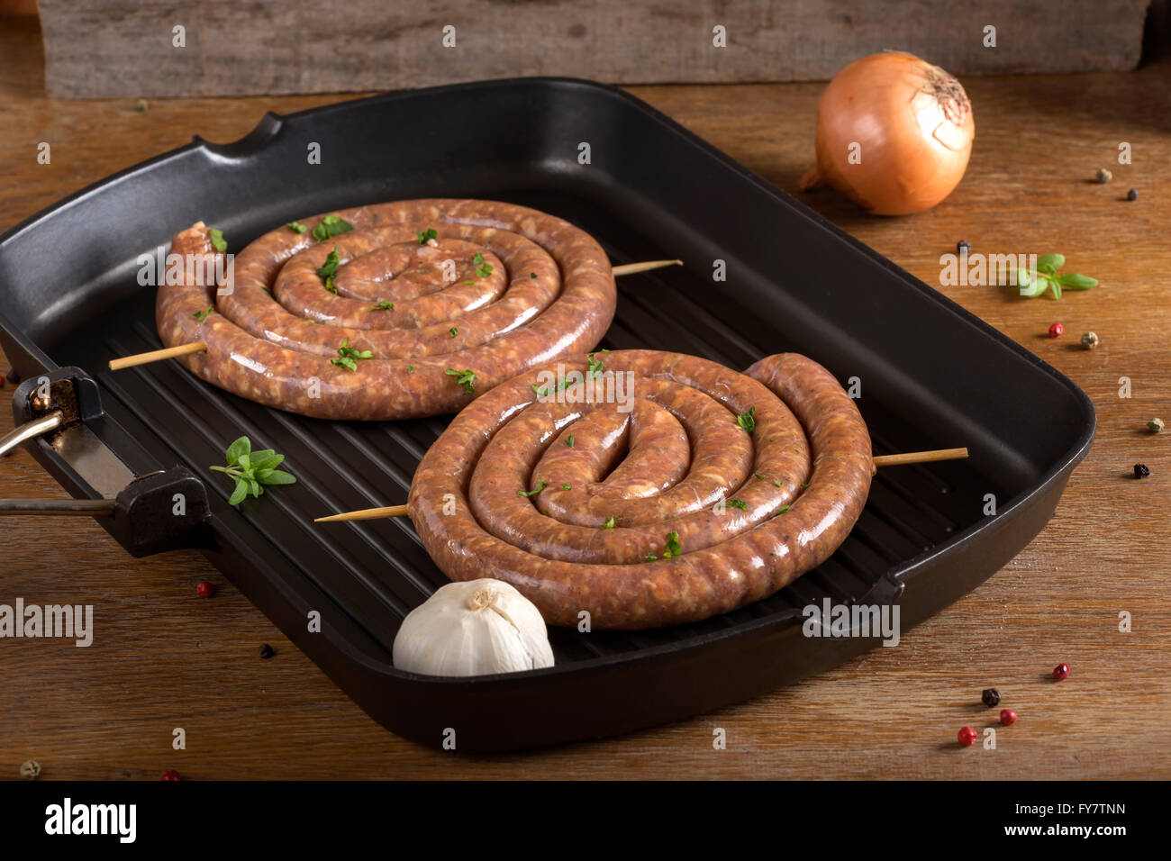 Two spiral raw sausages on a grilled pan Stock Photo Alamy