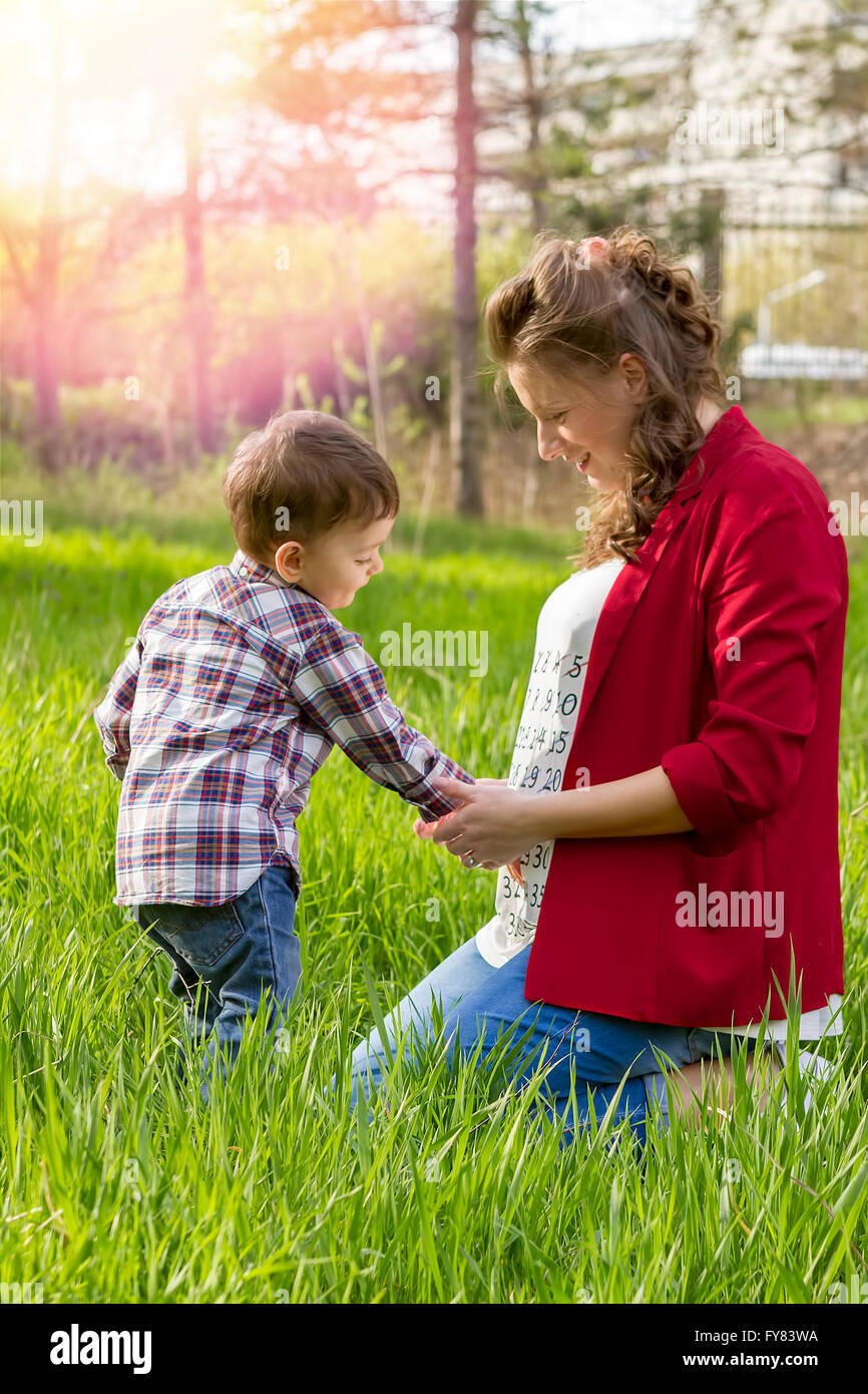 Beautiful pregnant woman outdoor with her happy little boy in the park. Stock Photo