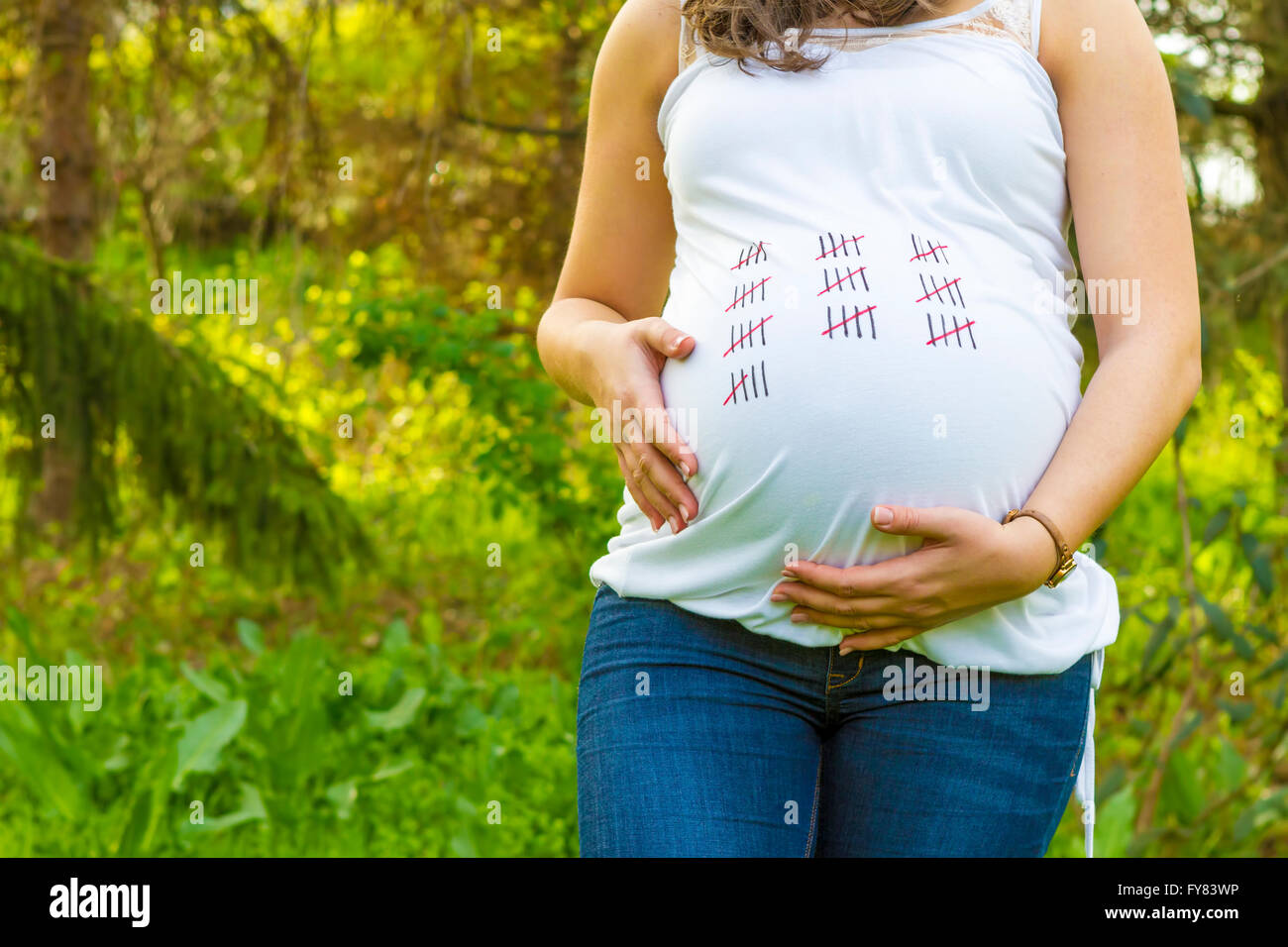 Pregnant young woman outdoors in warm summer day close up with calendar on her t-shirt. Stock Photo