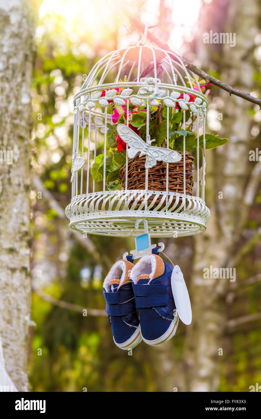 Blue baby shoes hanging from a cage and branch Stock Photo