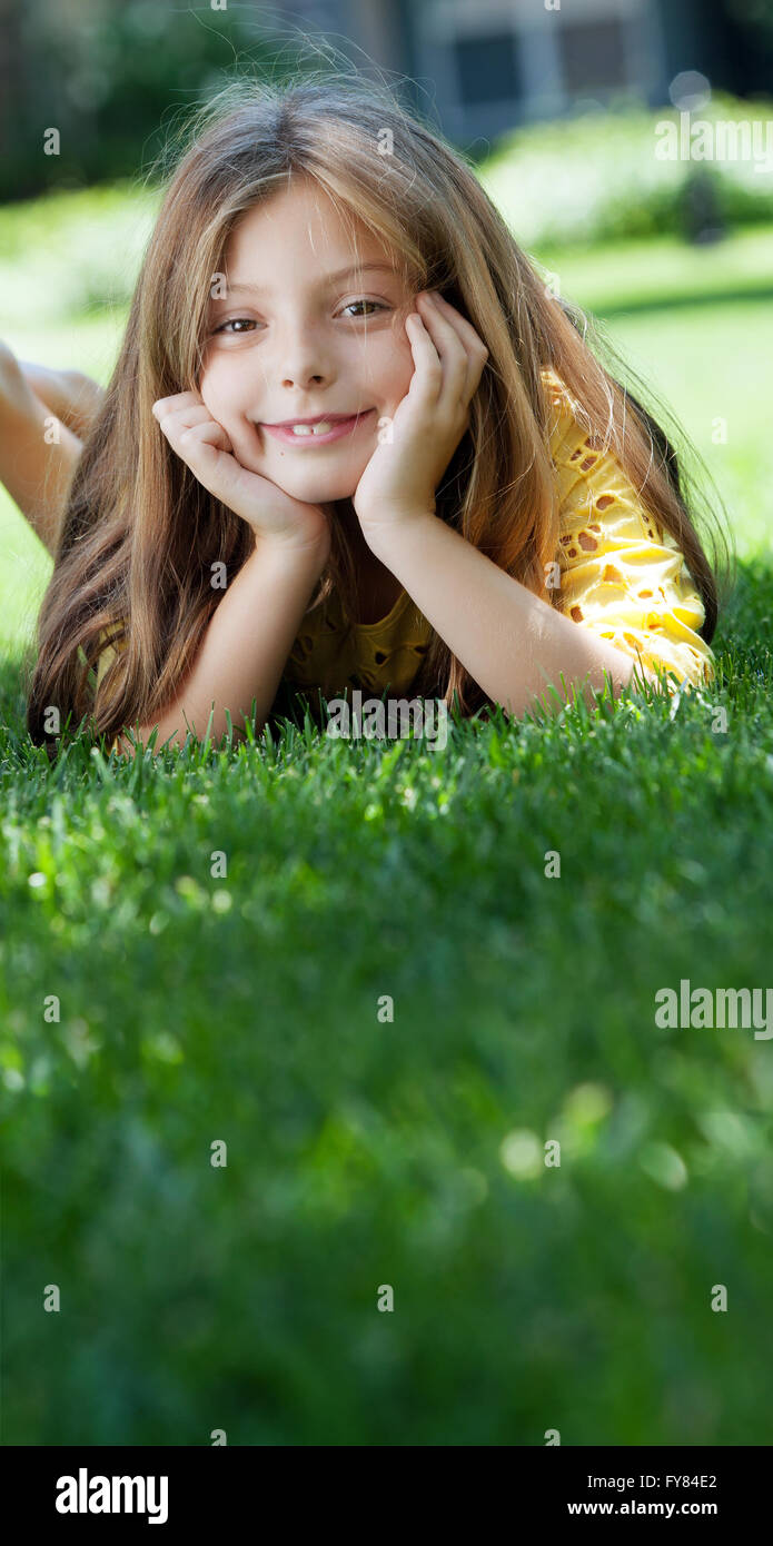 portrait of little girl laying on the grass in summer environment Stock ...