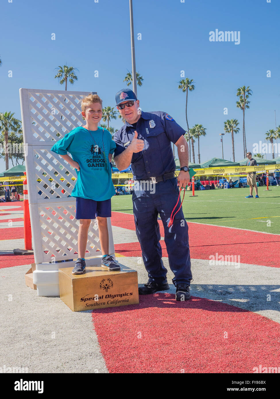 A disabled young boy 1012 receives his award from a uniformed fireman