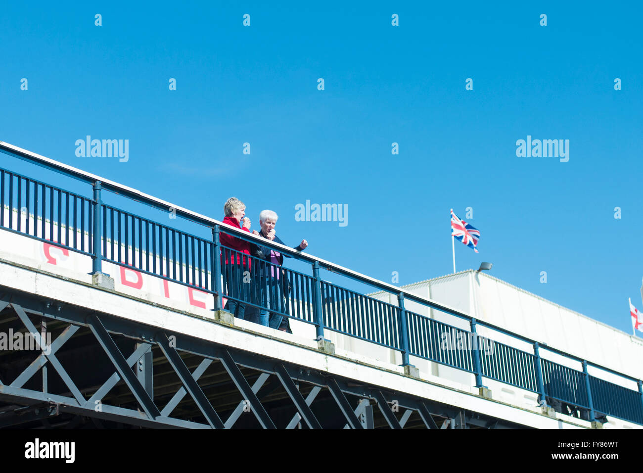 2 pensioners eat ice cream on the pier at southport with union jack flag in background Stock Photo