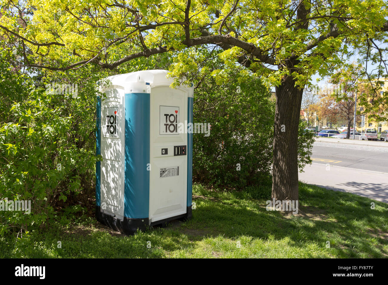 Portable Toi Toi toilet stands under a tree in a park Stock Photo
