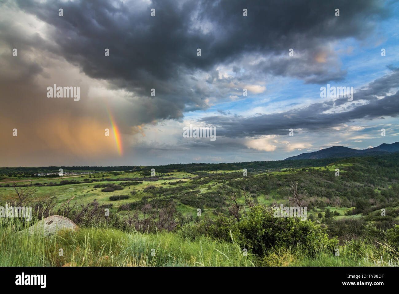A passing storm leaves a rainbow over the foothills of the Rocky Mountains at Cheyenne Mountain State Park near Colorado Springs Stock Photo