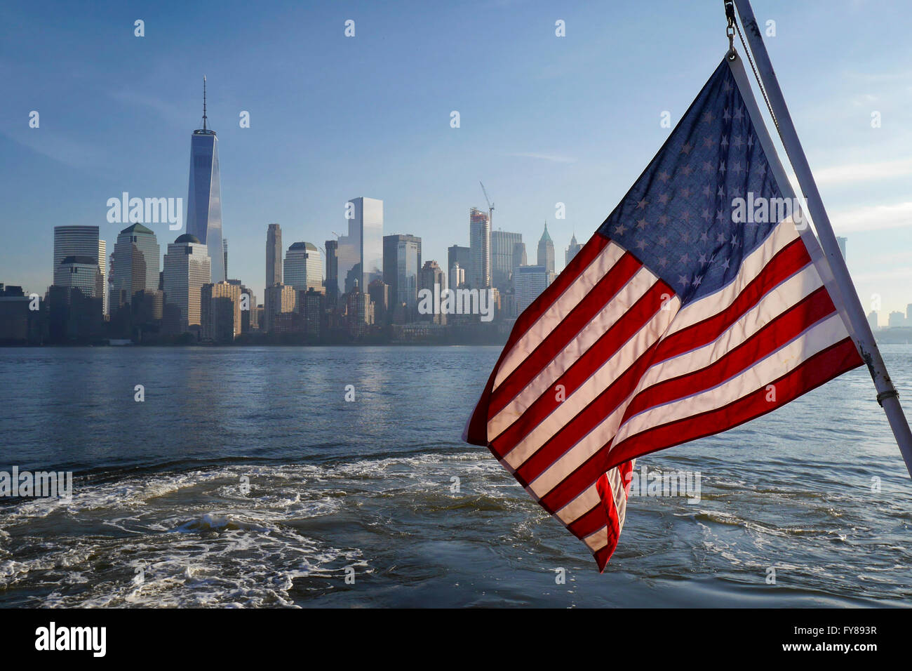 American flag and Manhattan skyline as seen from a ferry boat on New York Harbor Stock Photo