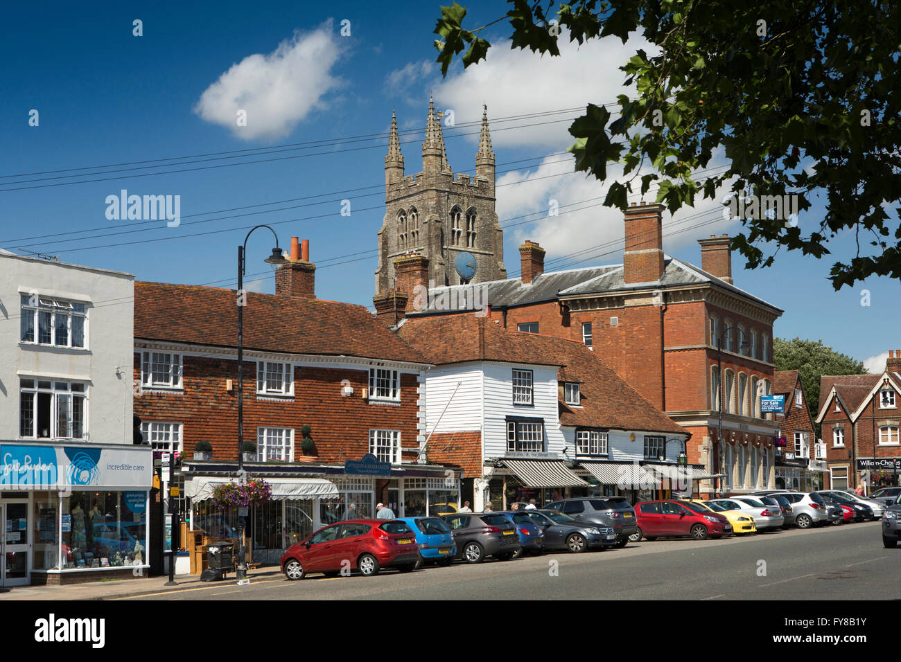 UK, Kent, Tenterden, St Mildred’s church tower above High Street shops in historic buildings Stock Photo