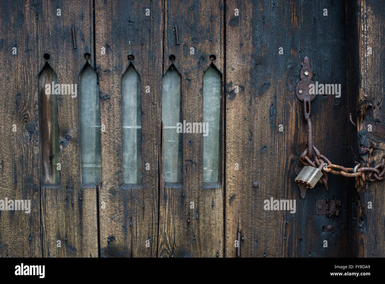 Padlocked chain, locked wooden door with arched window slits to an farm outhouse in castleton, Derbyshire. Stock Photo