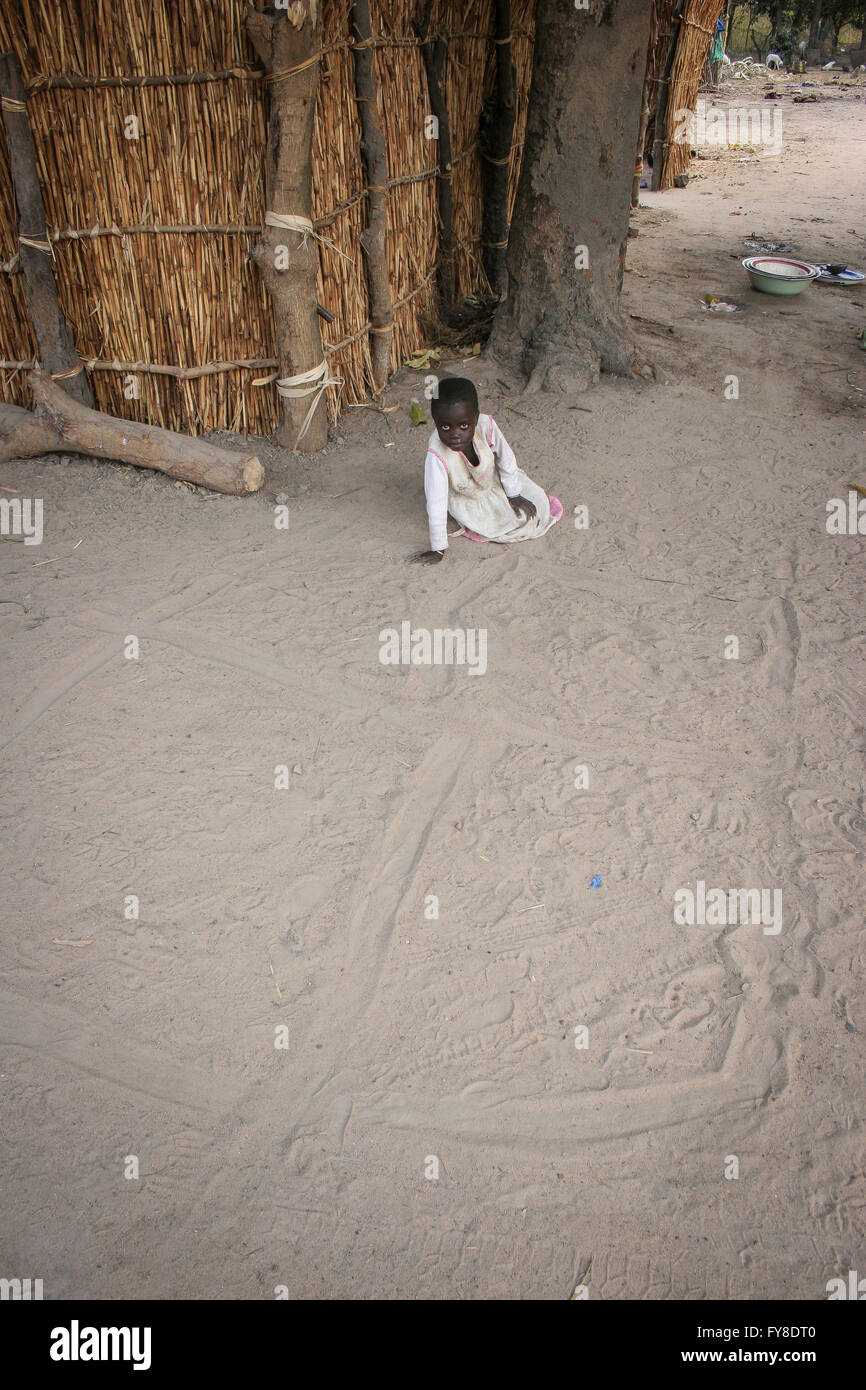 African young child drawing at the sand road outside the house, Gambia, Tanji village, Africa Stock Photo