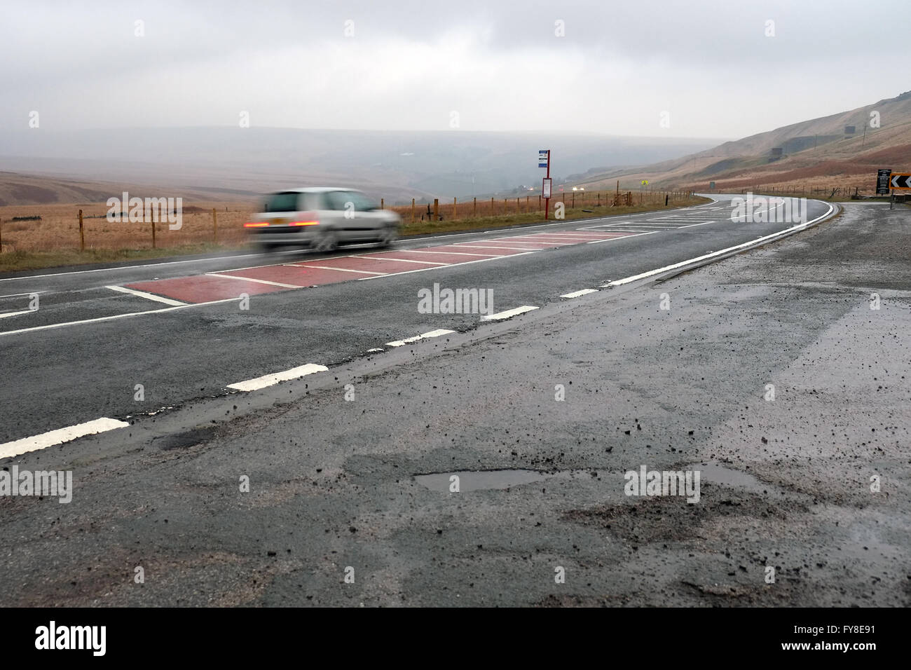 A car speeding along the A62 road in wet weather conditions near Marsden, Huddersfield, in the Yorkshire Pennines, England, UK. Stock Photo