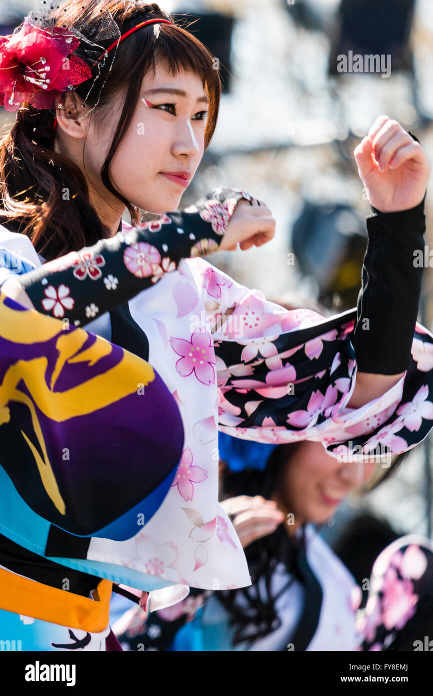 Young Japanese woman with red flower in hair, part of dance team, dancing in colourful costume during Yosakoi dance festival at Kumamoto, Japan. Stock Photo