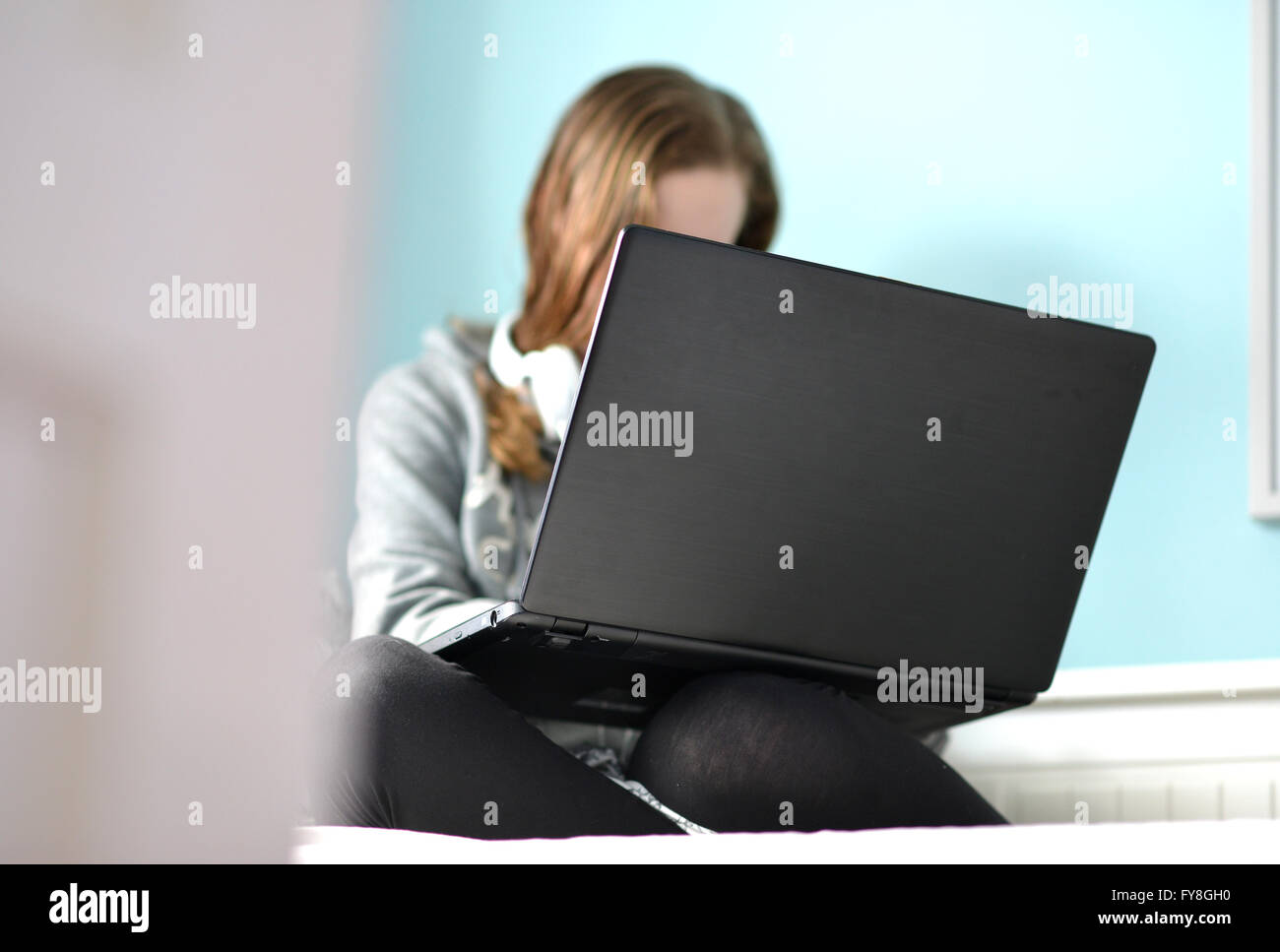 Teen girl on a laptop in her bedroom Stock Photo