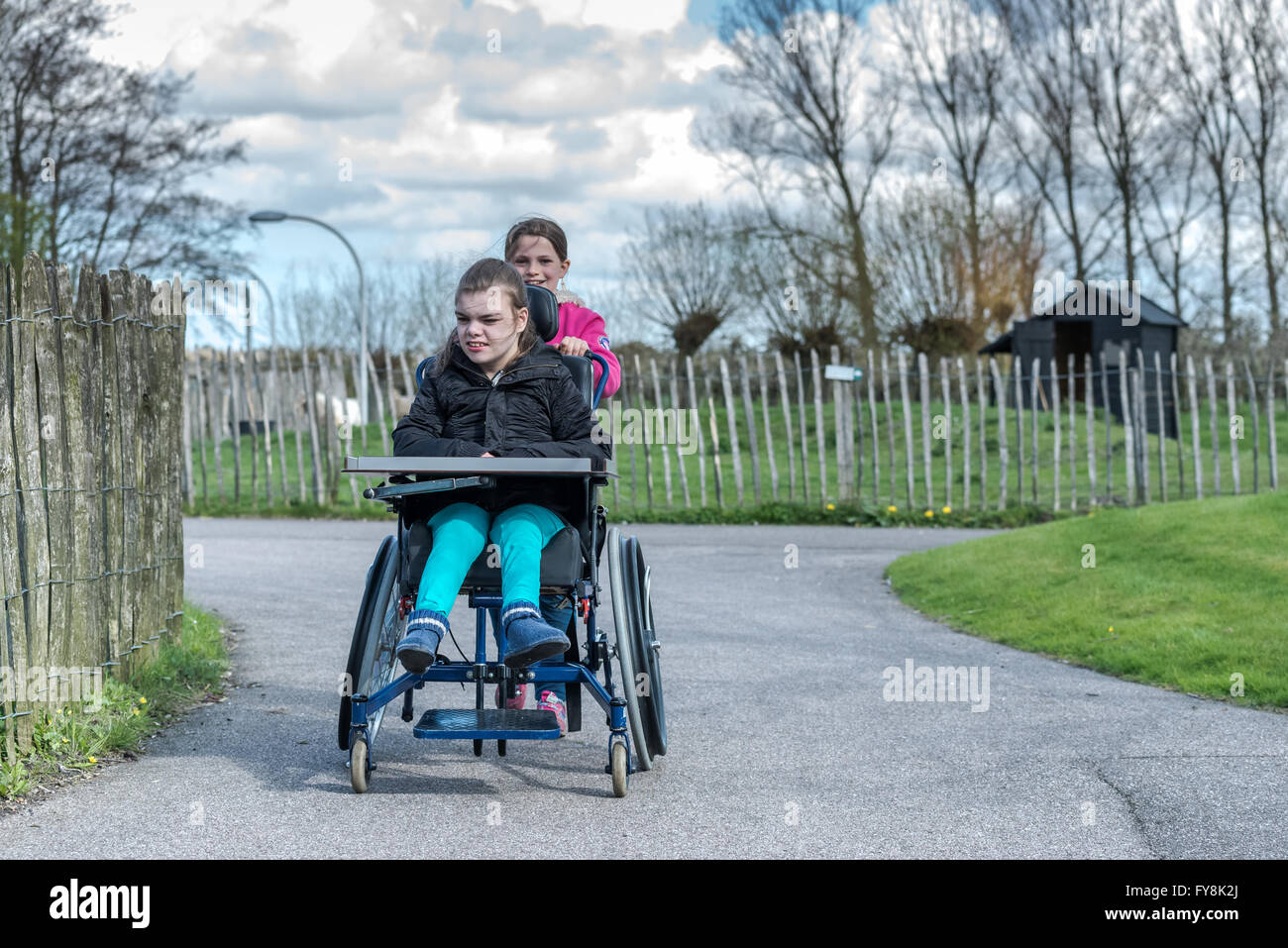 A disabled person in a wheelchair relaxing outside with her sister Stock Photo