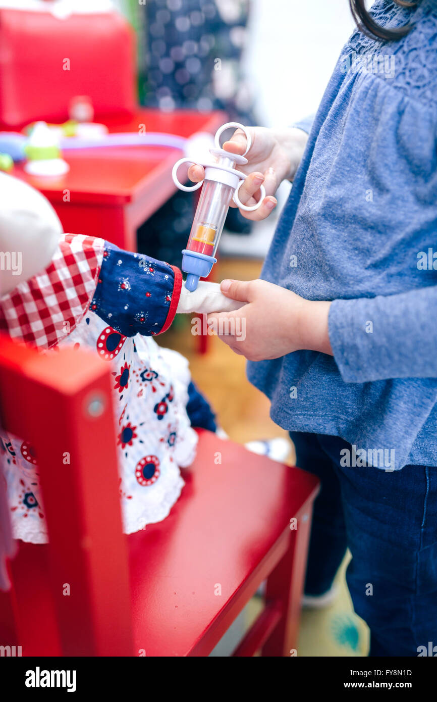 Little girl giving injection to her doll, close-up Stock Photo - Alamy
