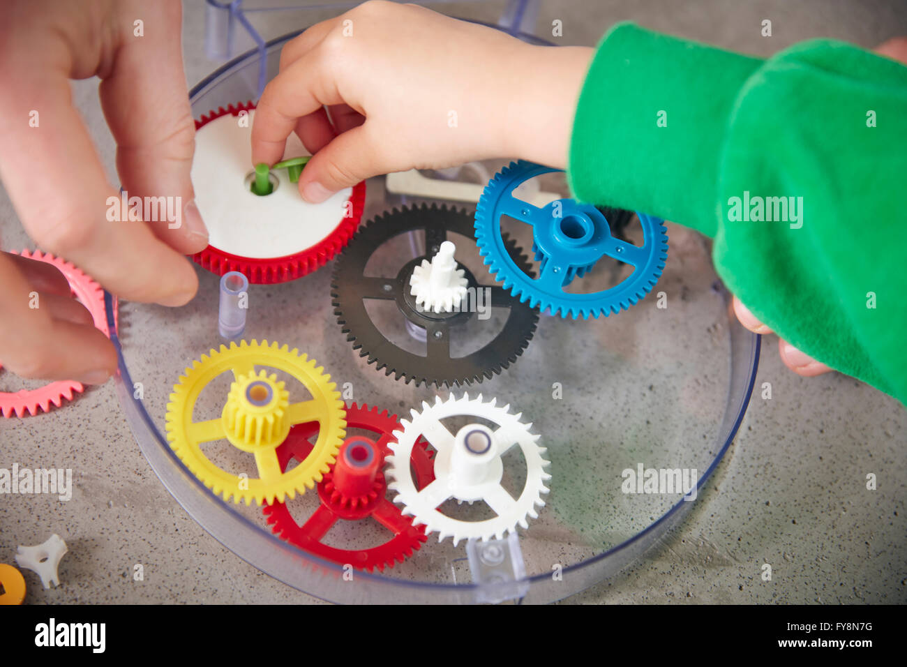 Hands assembling plastic cogwheels Stock Photo