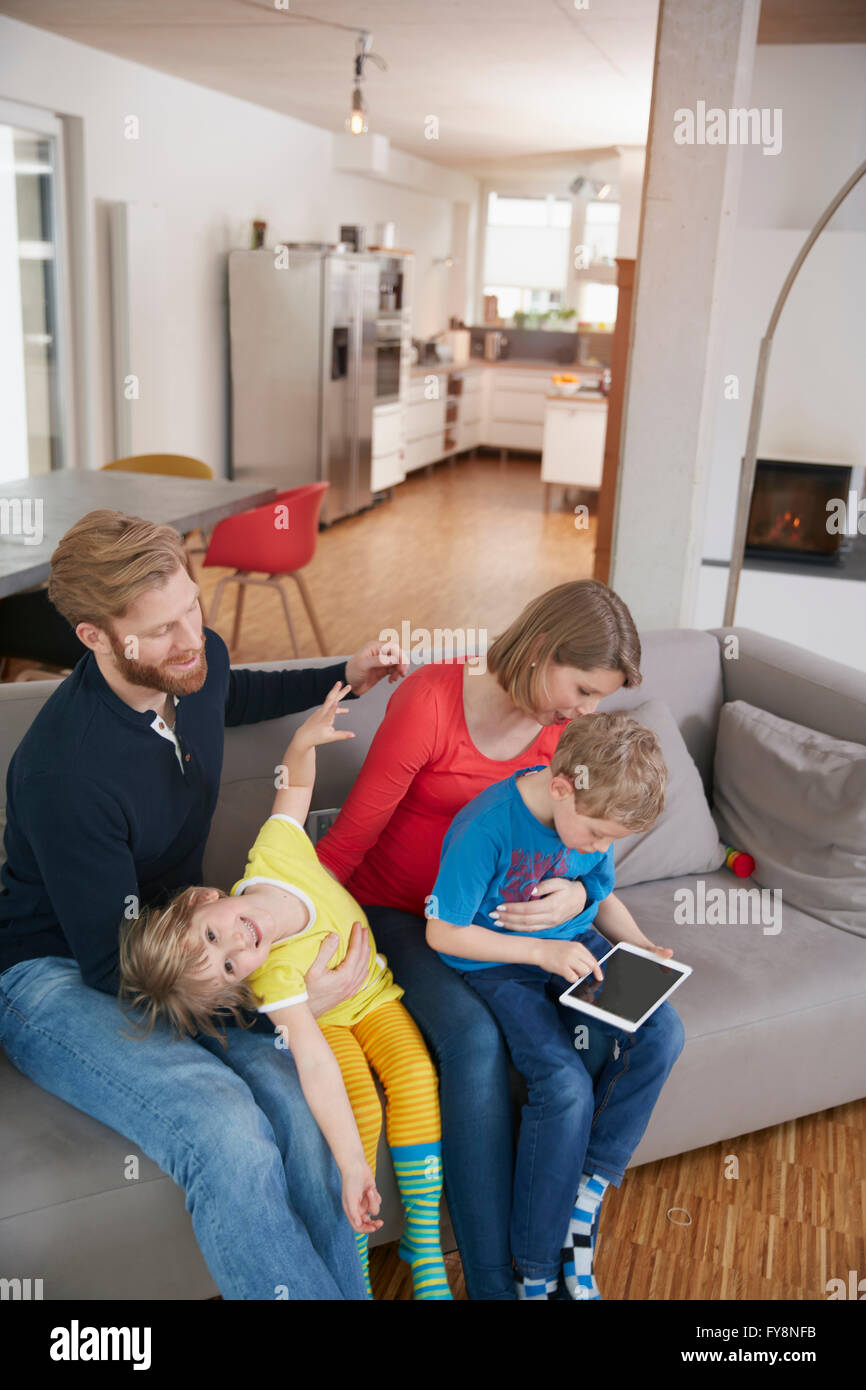 Family of four with digital tablet on couch Stock Photo