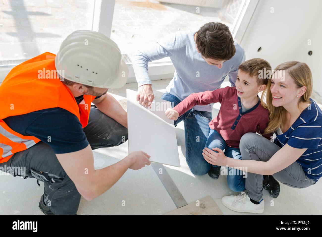 Construction worker showing family tile sample Stock Photo - Alamy