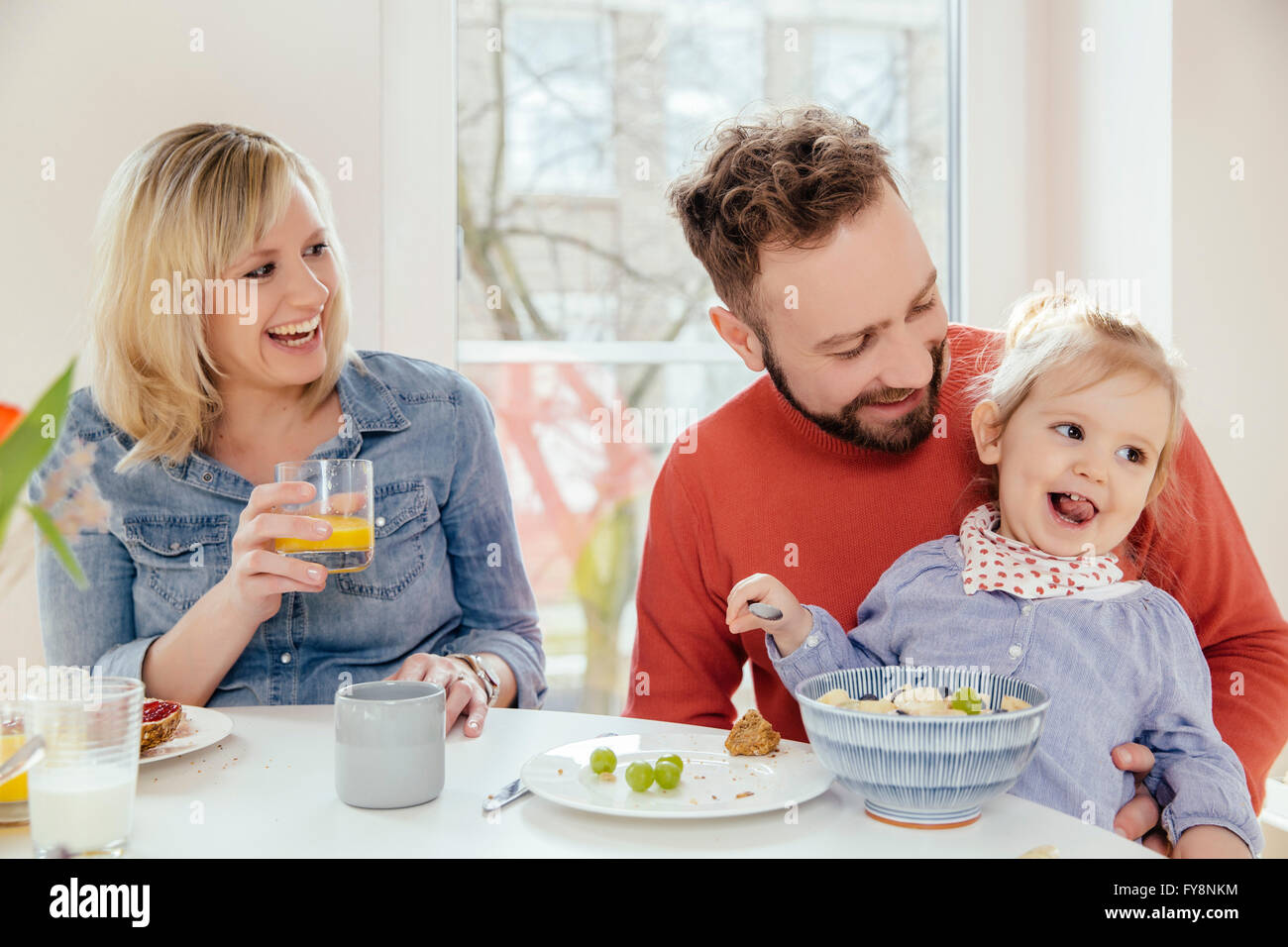 Little girl eating muesli with fruit at breakfast table Stock Photo