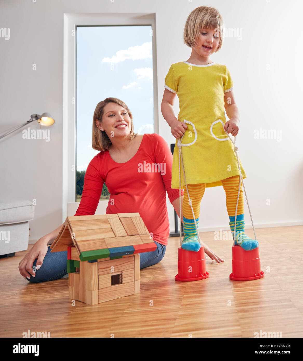 Mother with daughter walking on buckets at home Stock Photo Alamy