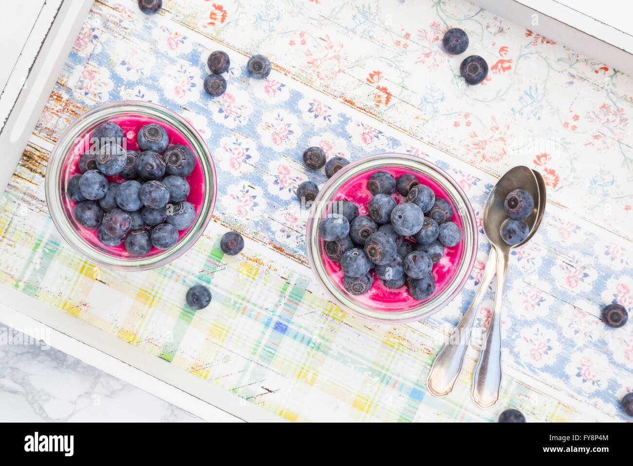 Two glasses of overnight oats with blueberries and berry juice on wooden tray Stock Photo