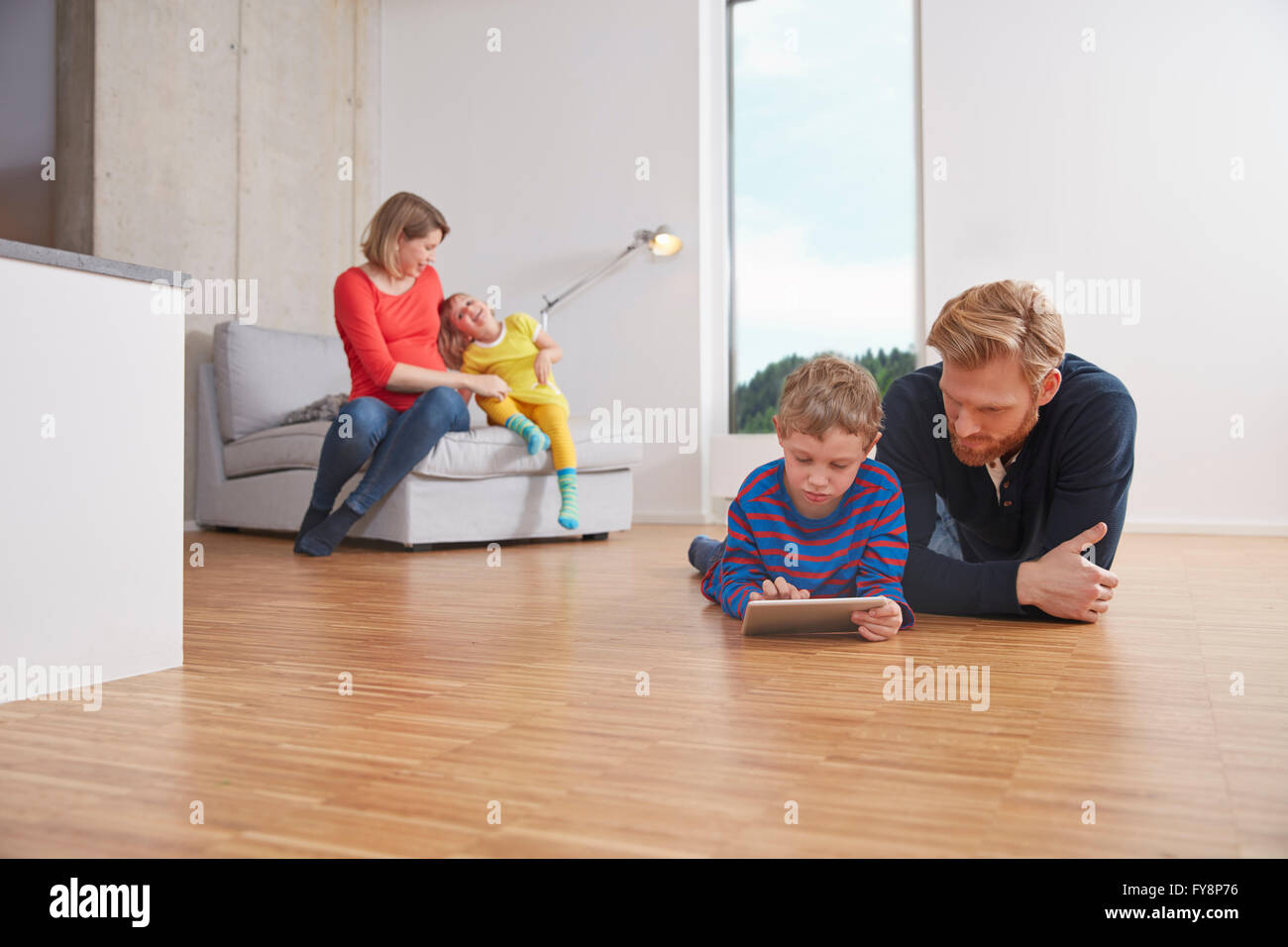 Fathar and son with digital tablet lying on floor Stock Photo
