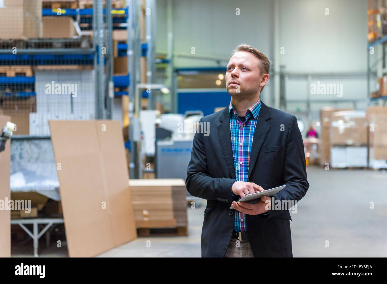 Manager checking goods in storage hall of factory Stock Photo - Alamy