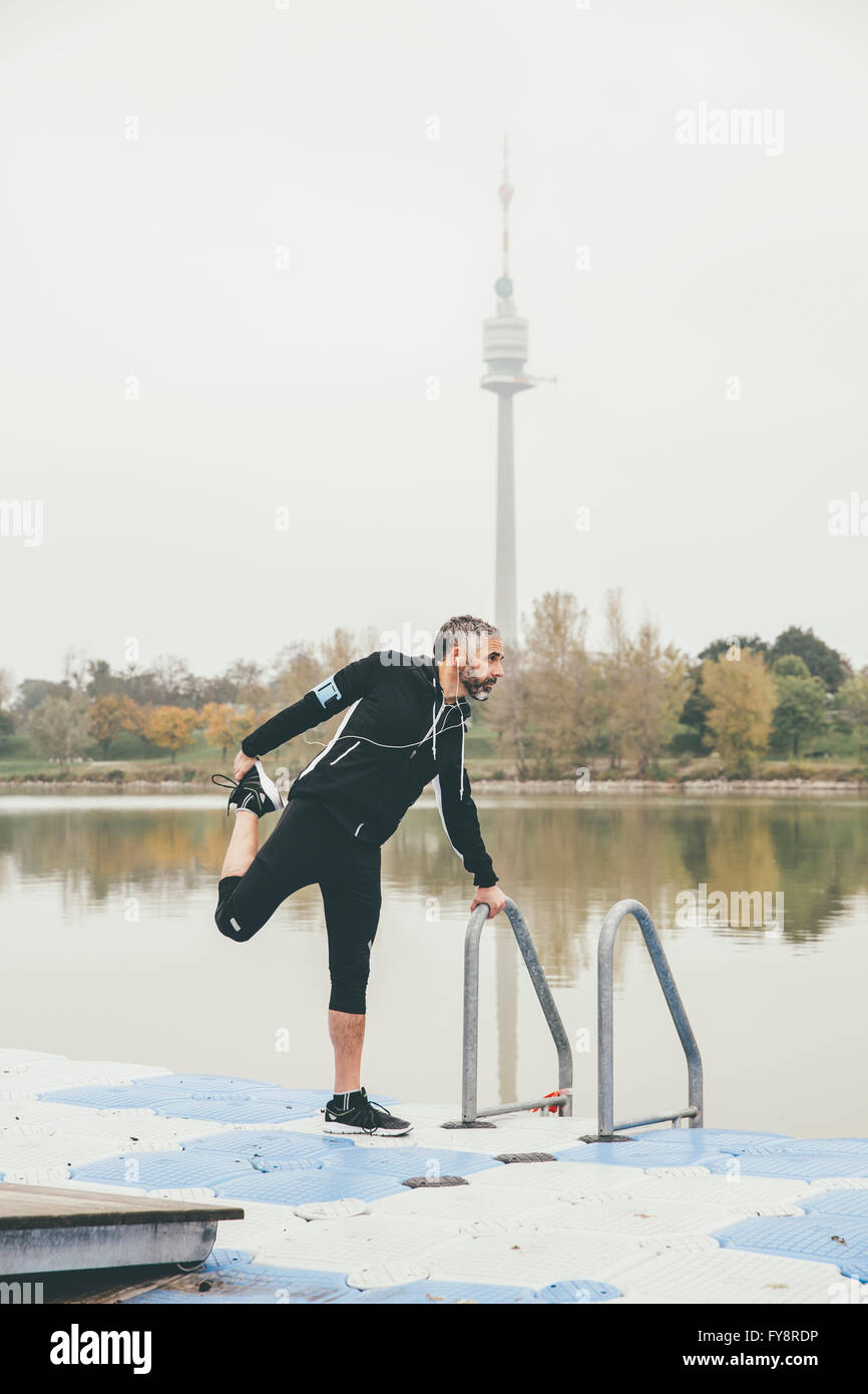 Austria, Vienna, jogger doing stretching exercise on Danube Island Stock Photo