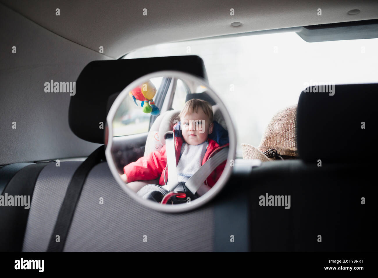 Mirror reflection of toddler sitting in child's seat in a car Stock Photo