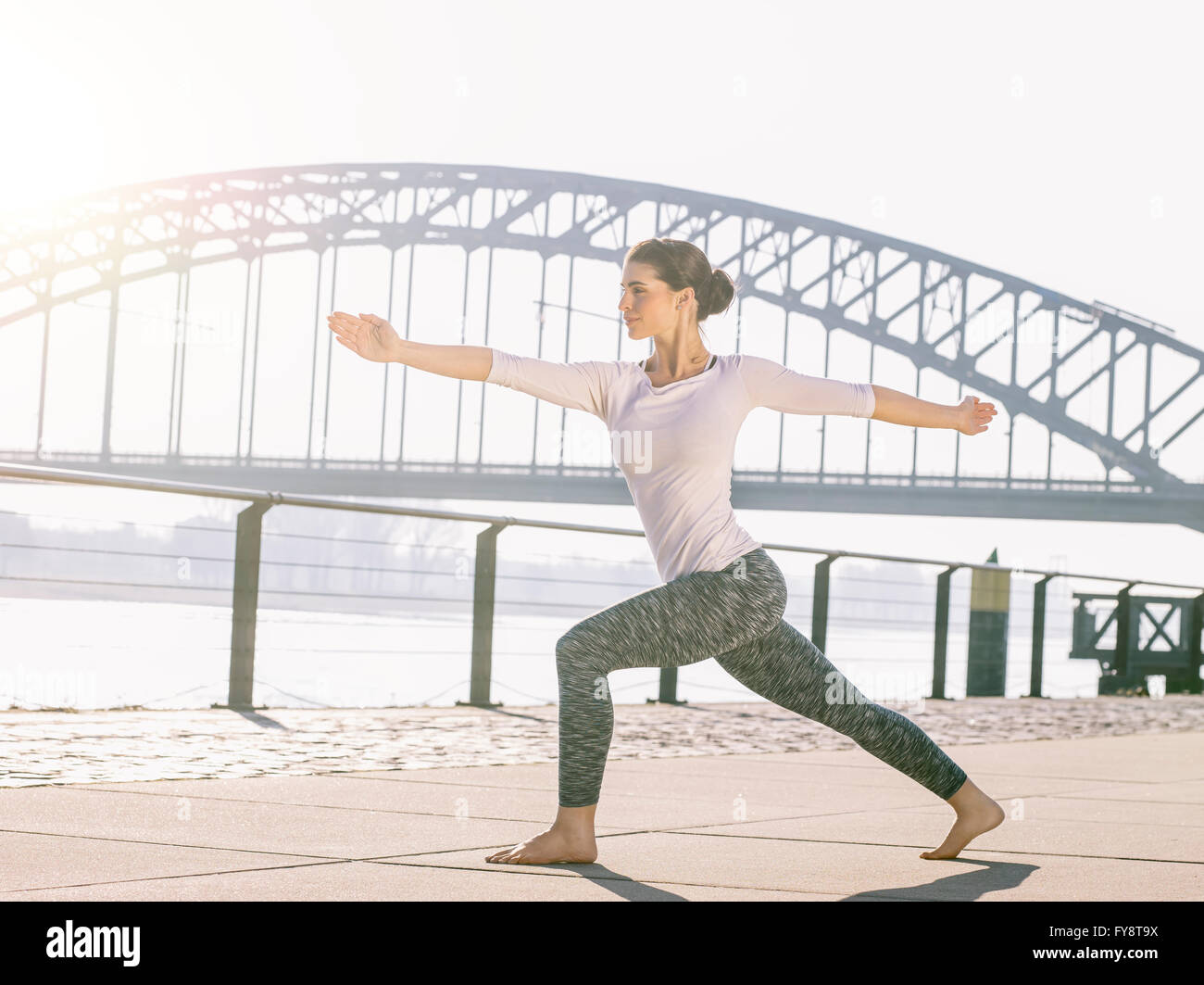 Germany, Cologne, young woman practicing yoga, warrior pose Stock Photo