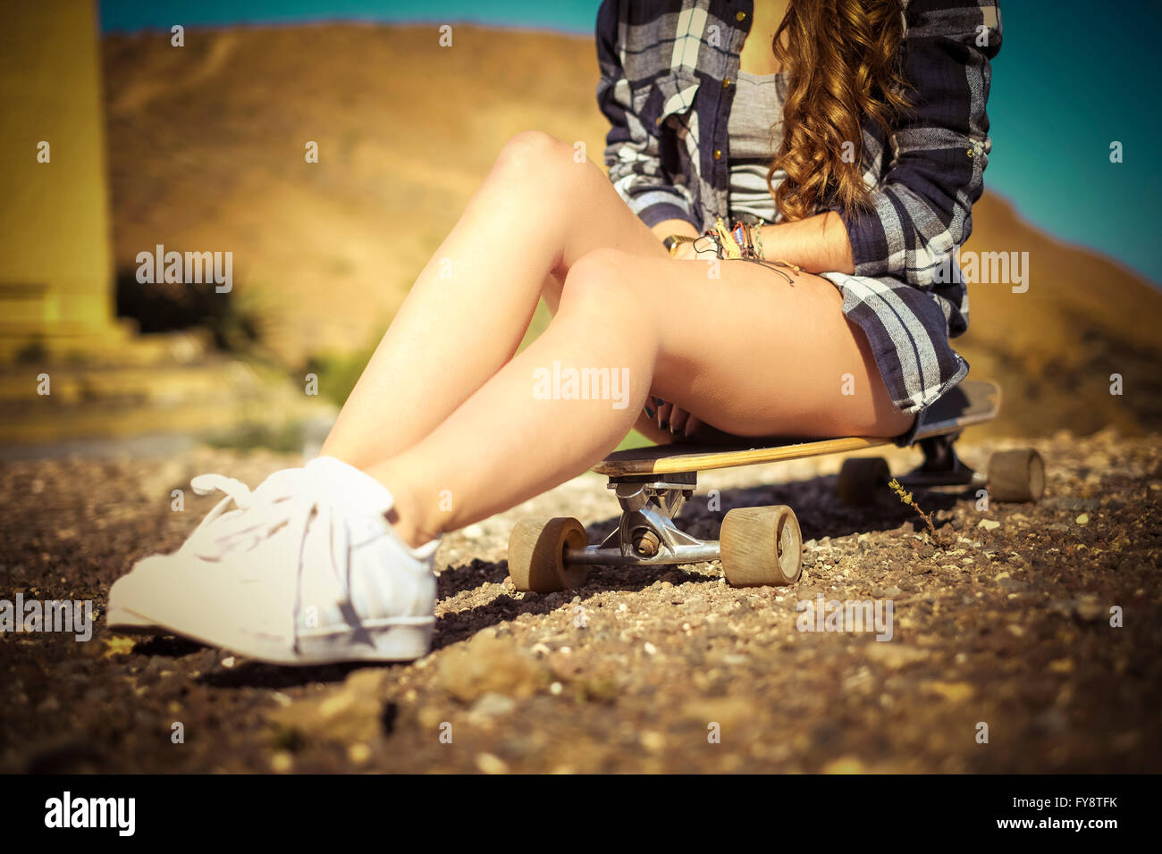 Teenage girl sitting on longboard, partial view Stock Photo - Alamy
