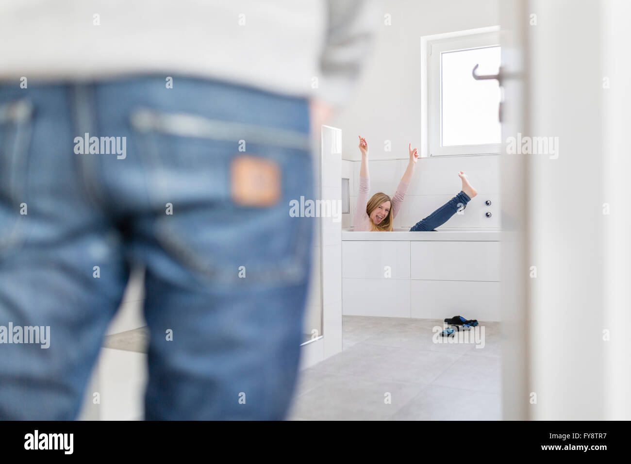 Woman sitting in bathtub of her new home crying for joy while her friend watching her Stock Photo