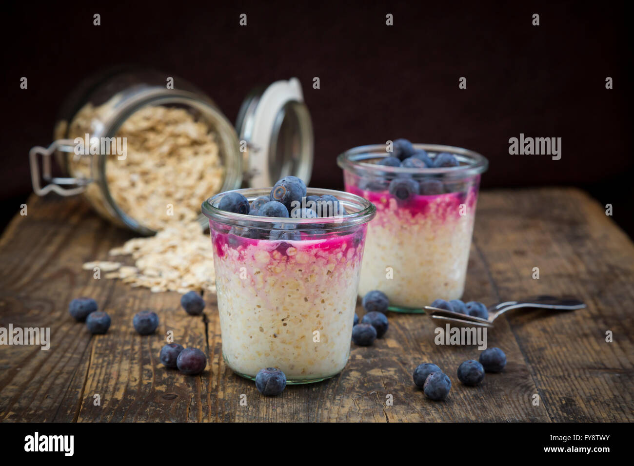 Two glasses of overnight oats with blueberries and berry juice on wood Stock Photo