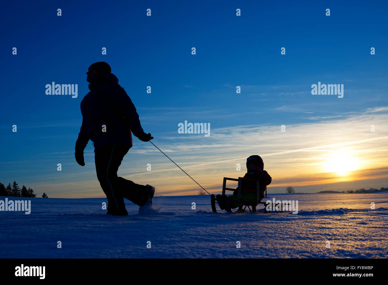 Mother and daughter sledging at sunset Stock Photo