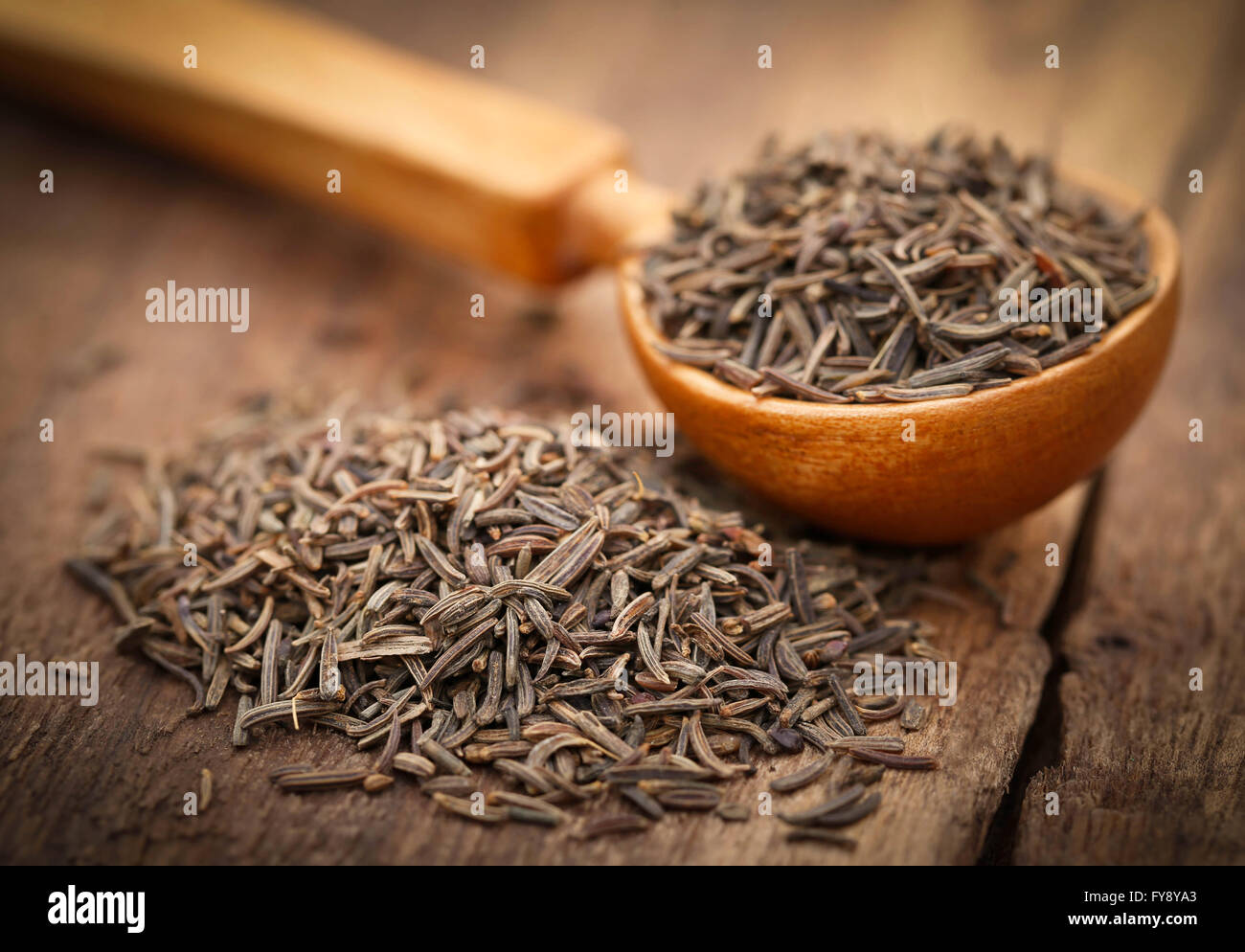 Caraway seeds in a spoon on wooden surface Stock Photo