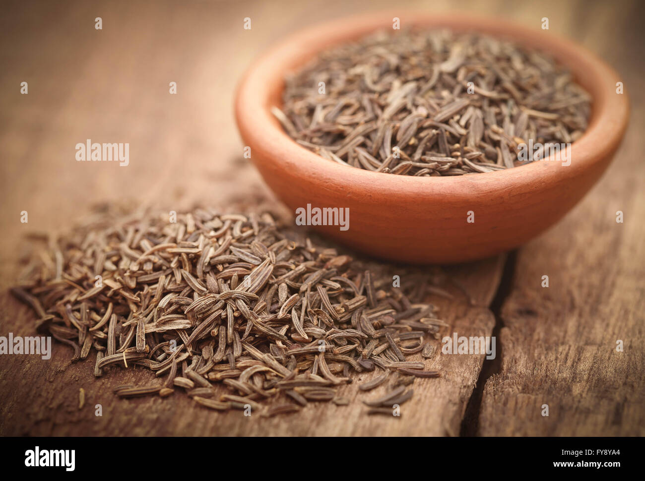 Caraway seeds in a pottery on wooden surface Stock Photo