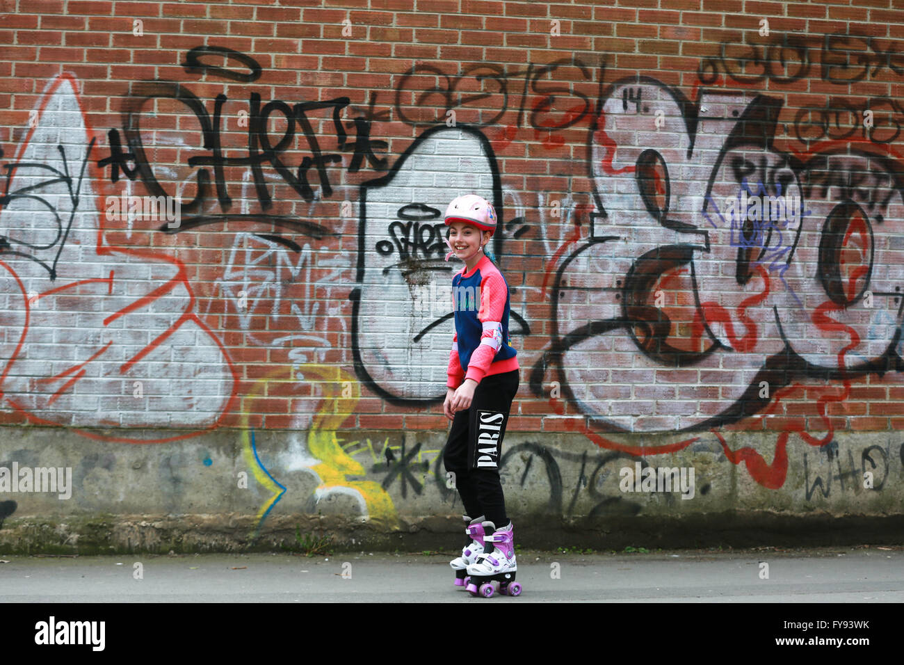 young girl learning to roller skate in the park against a graffiti