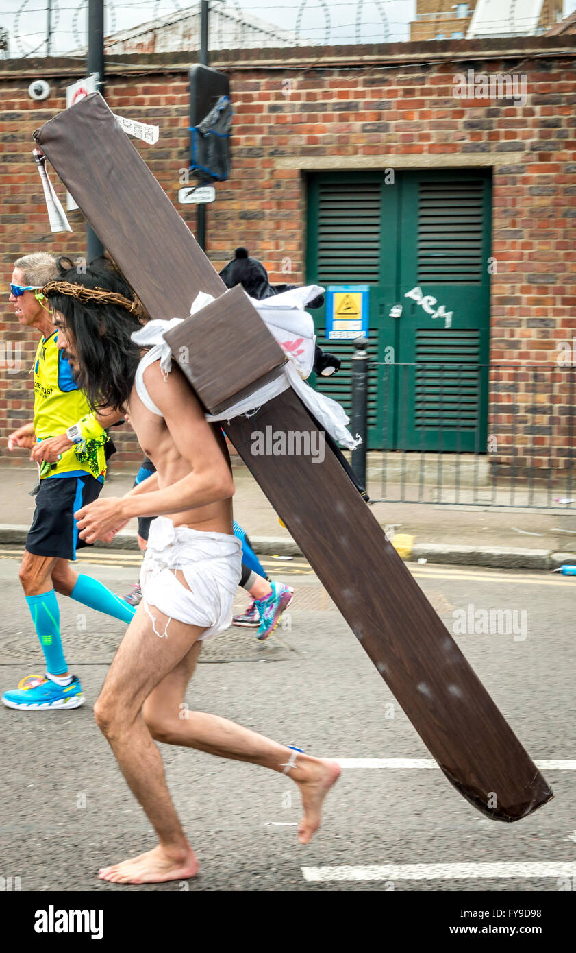 London, UK. 24th April, 2016. London Marathon 2016. Runners in great costumes.  Barefoot runner as Jesus with a cross on his back Credit:  Elena Chaykina/Alamy Live News Stock Photo