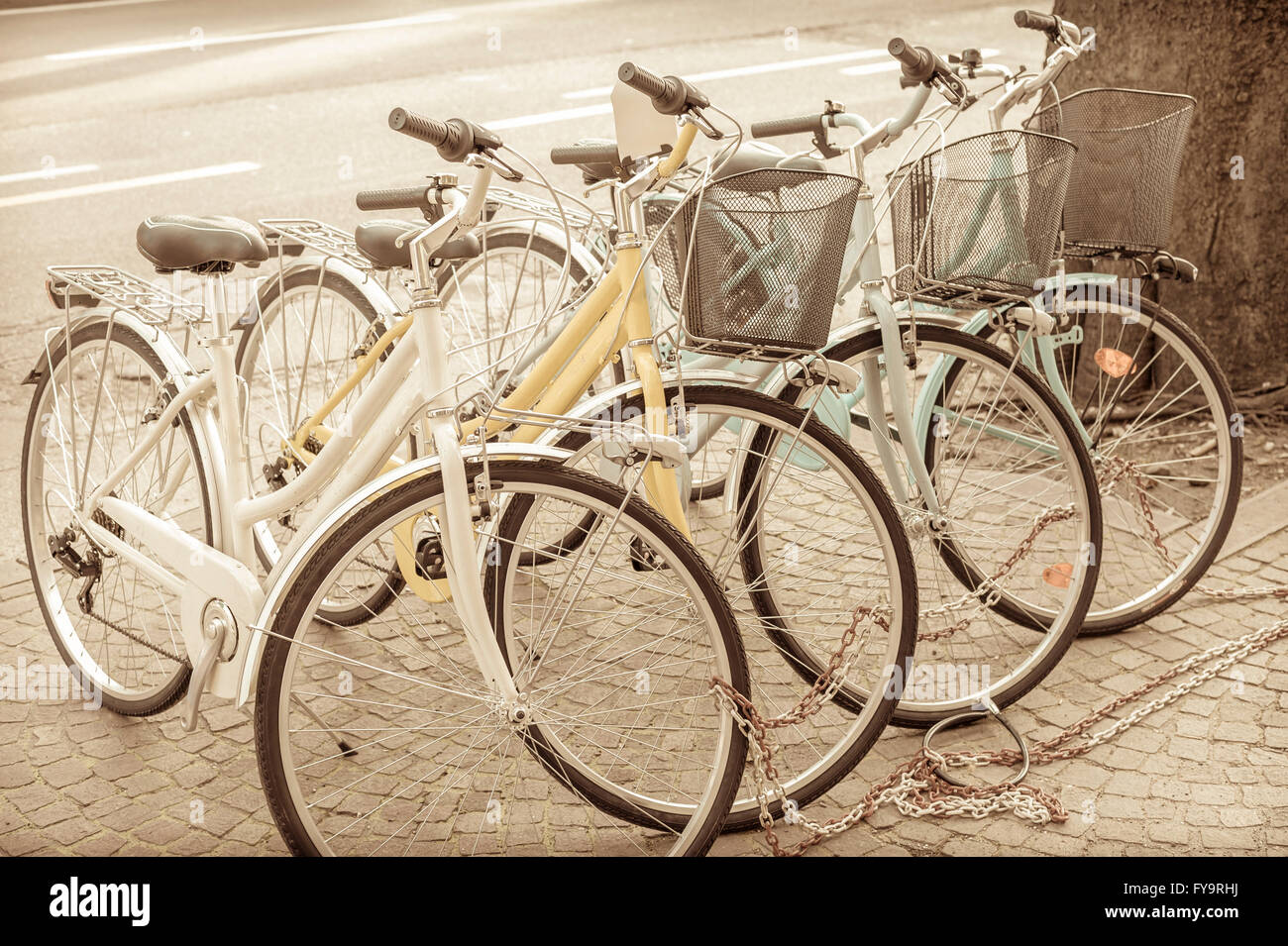 Four parked bicycles on the sidewalk, chained together.  Vintage effect. Stock Photo