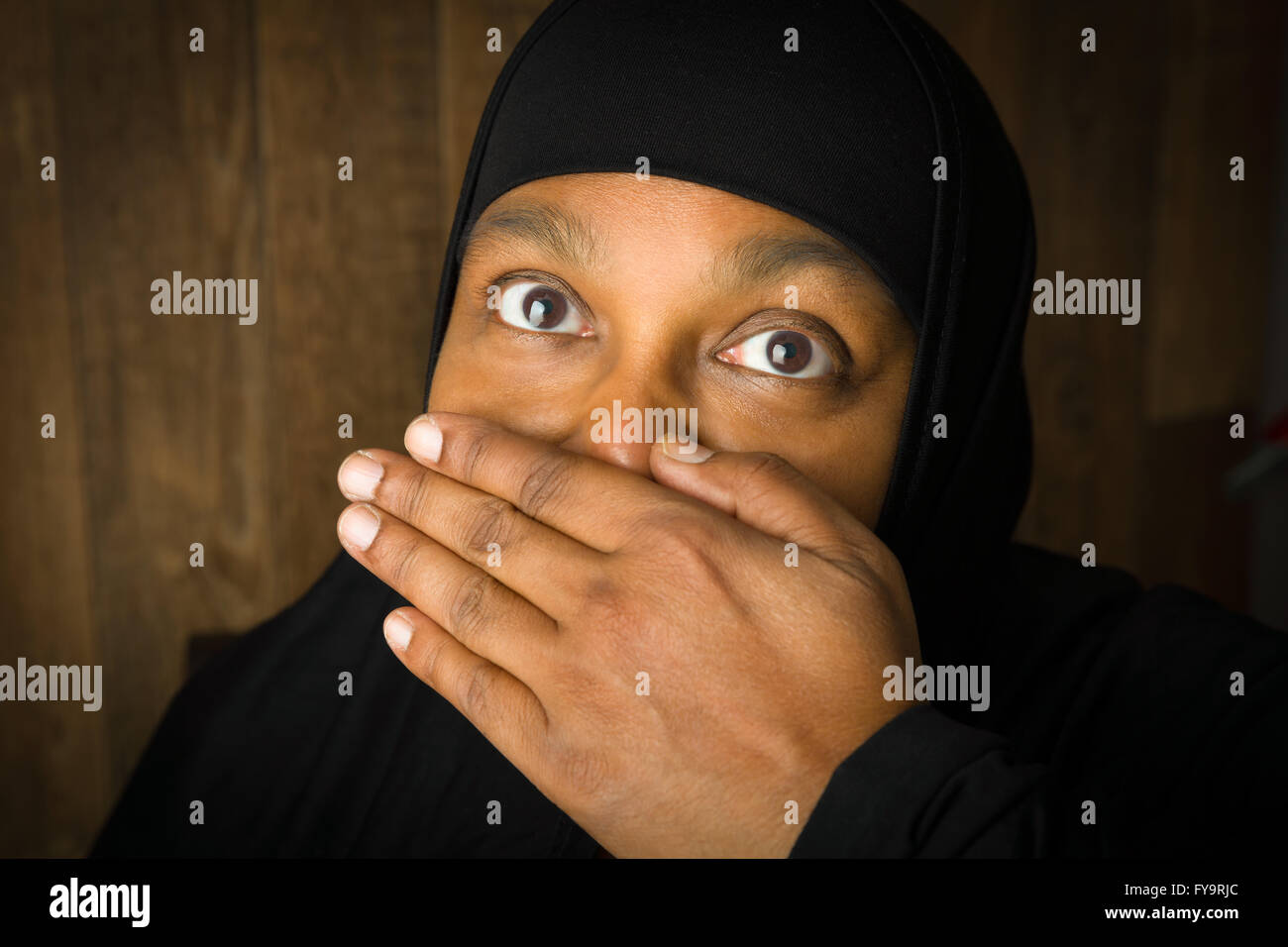 Muslim woman of African descent holding her hand in front of her mouth Stock Photo