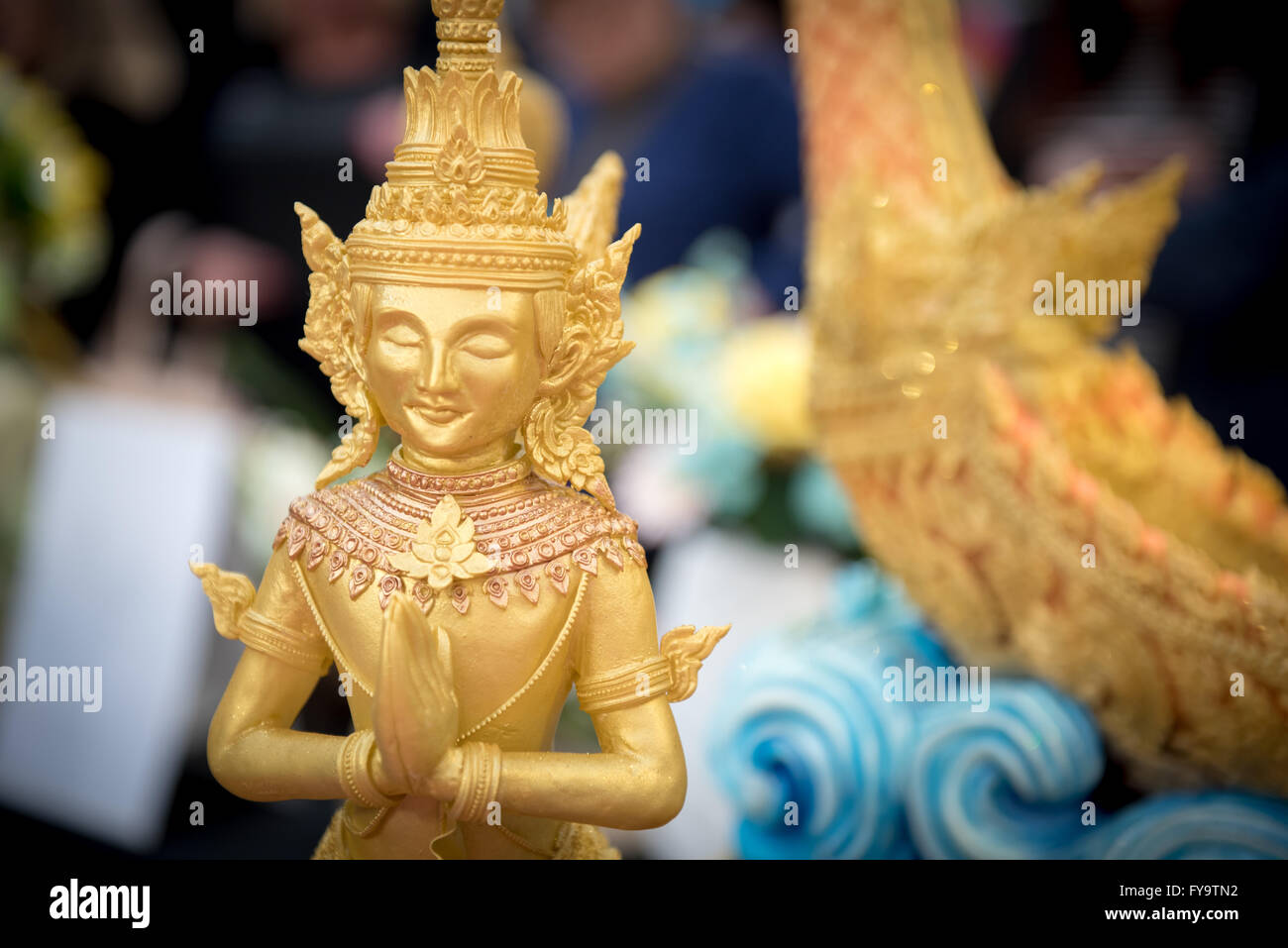 Thai inspired cake with edible golden figures at Cake International – The Sugarcraft, Cake Decorating and Baking Show in London. Stock Photo