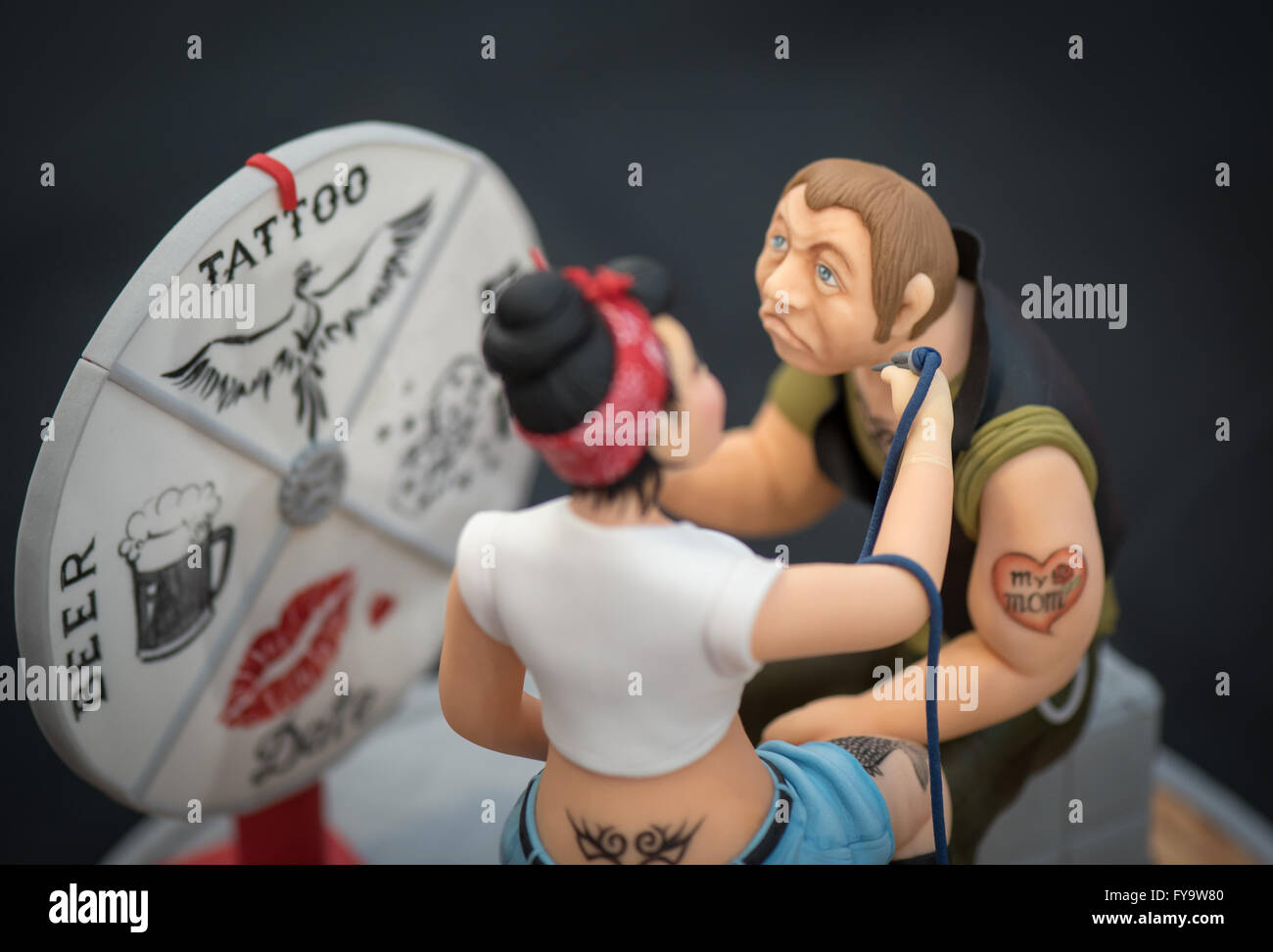 Tattoo studio woman and man cake decorations at Cake International – The Sugarcraft, Cake Decorating and Baking Show in London Stock Photo