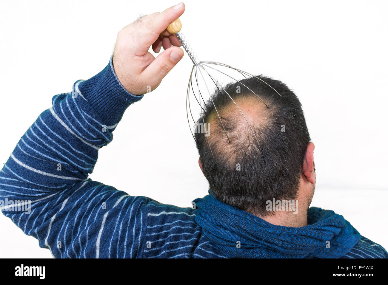 Man relaxes with the Genie head massager. Alternative Therapy. Indian head massage tool, self head massager. Stock Photo