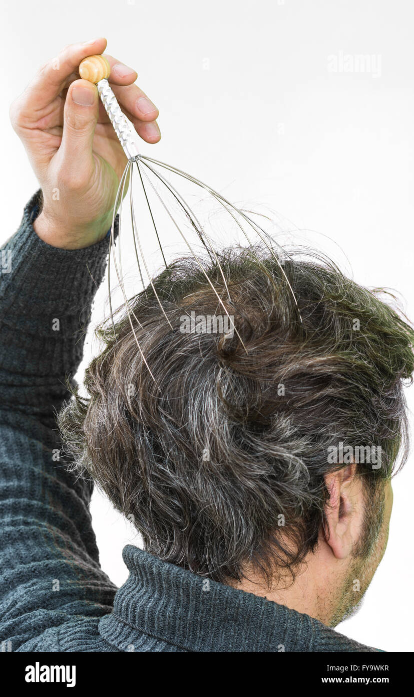 Man relaxes with the Genie head massager. Alternative Therapy. Indian head massage tool, self head massager. Stock Photo