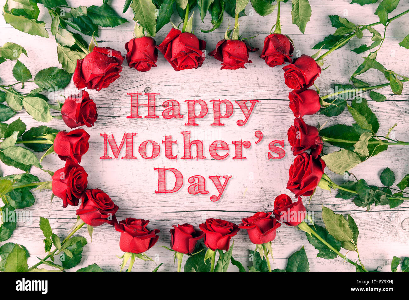 https://c8.alamy.com/comp/FY9XHJ/happy-mothers-day-text-in-a-circle-of-red-roses-on-wooden-table-top-FY9XHJ.jpg