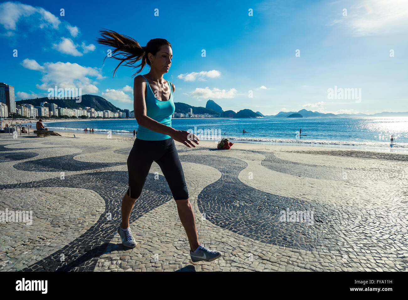 RIO DE JANEIRO - APRIL 3, 2016: A Brazilian fitness walker passes along a bright morning view of the Copacabana boardwalk. Stock Photo