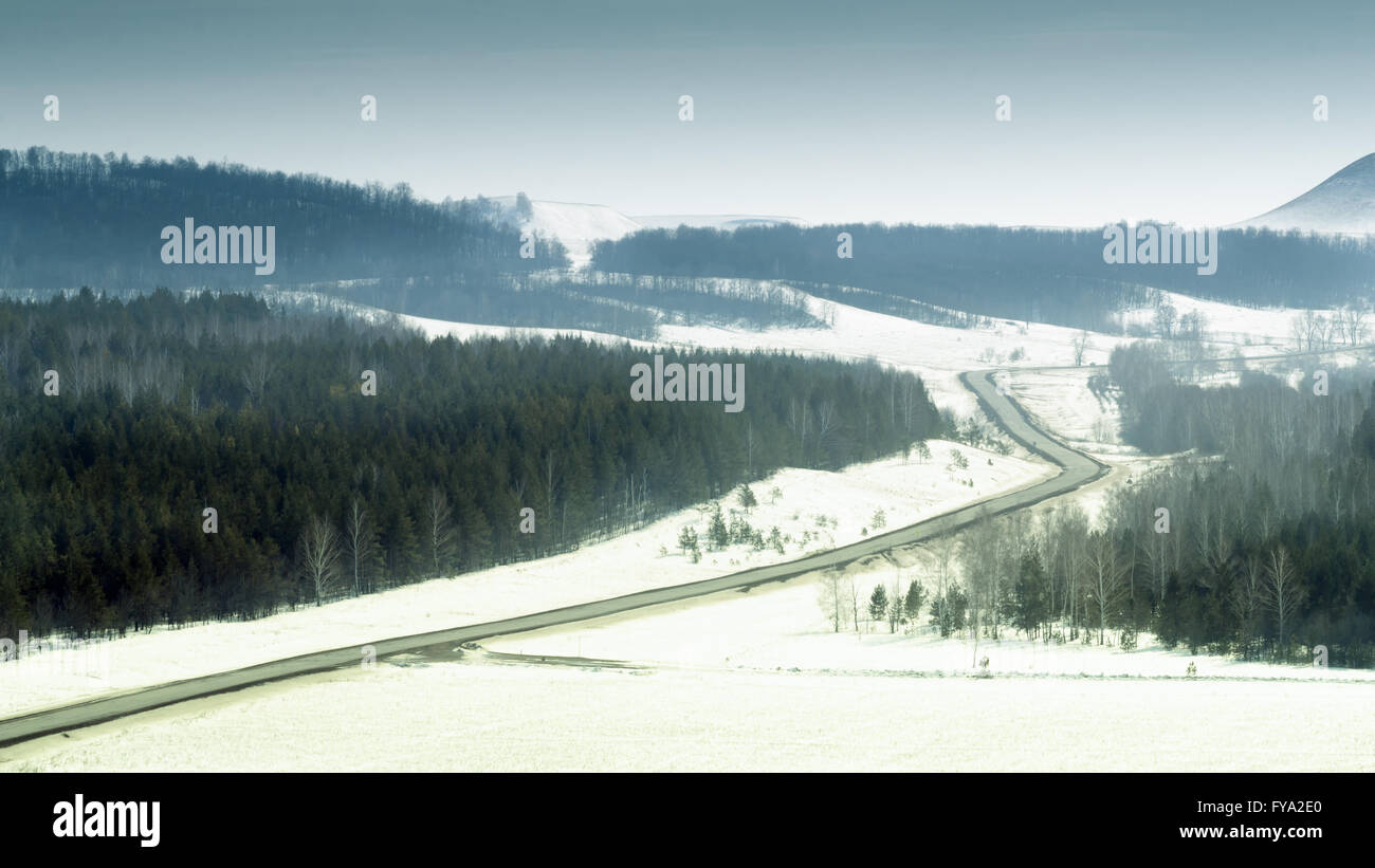 Winter travel scene of a road going through a black forest with snow ...