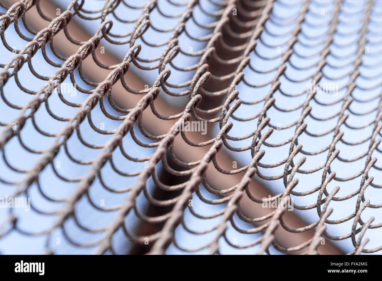 Closeup details of a wire chain link fence with defocused area and blue sky background Stock Photo