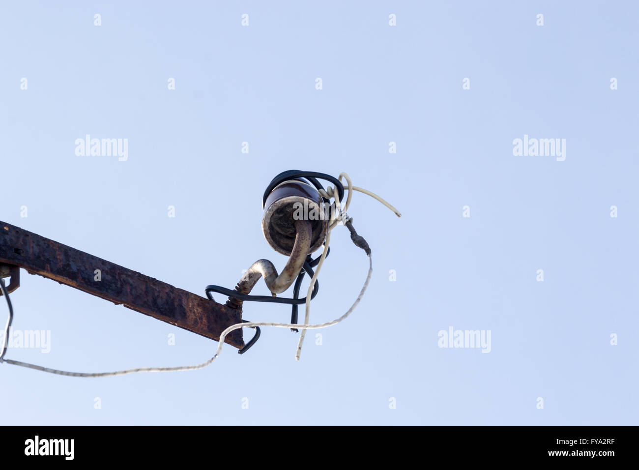 Single broken power insulator on a metal pole with clear sky Stock Photo