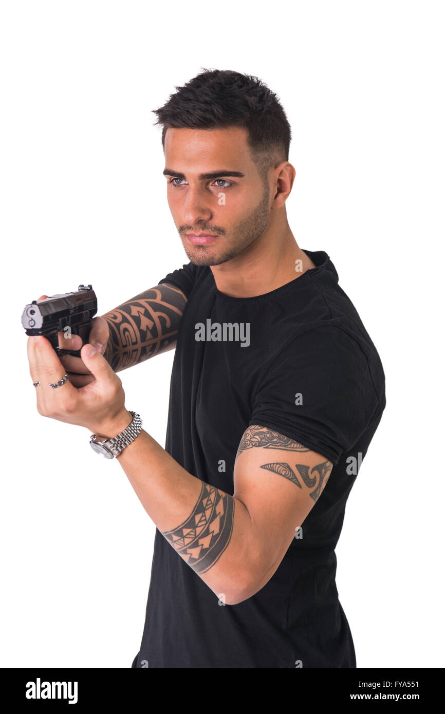Young handsome man pointing gun, wearing black t-shirt, isolated on white background Stock Photo